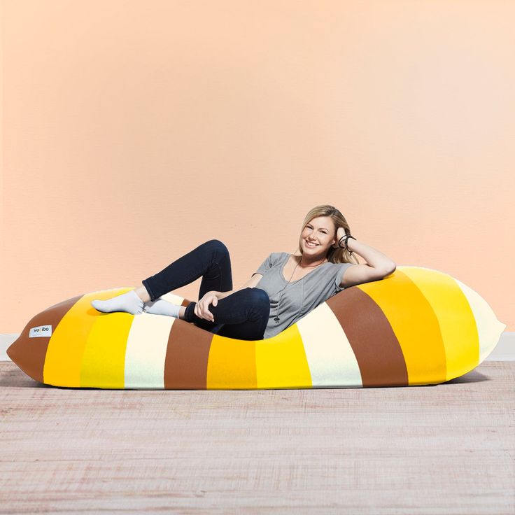 A woman sitting on a bean bag chair in front of a pink wall and floor A woman sitting on a bean bag chair in front of a pink wall and floor